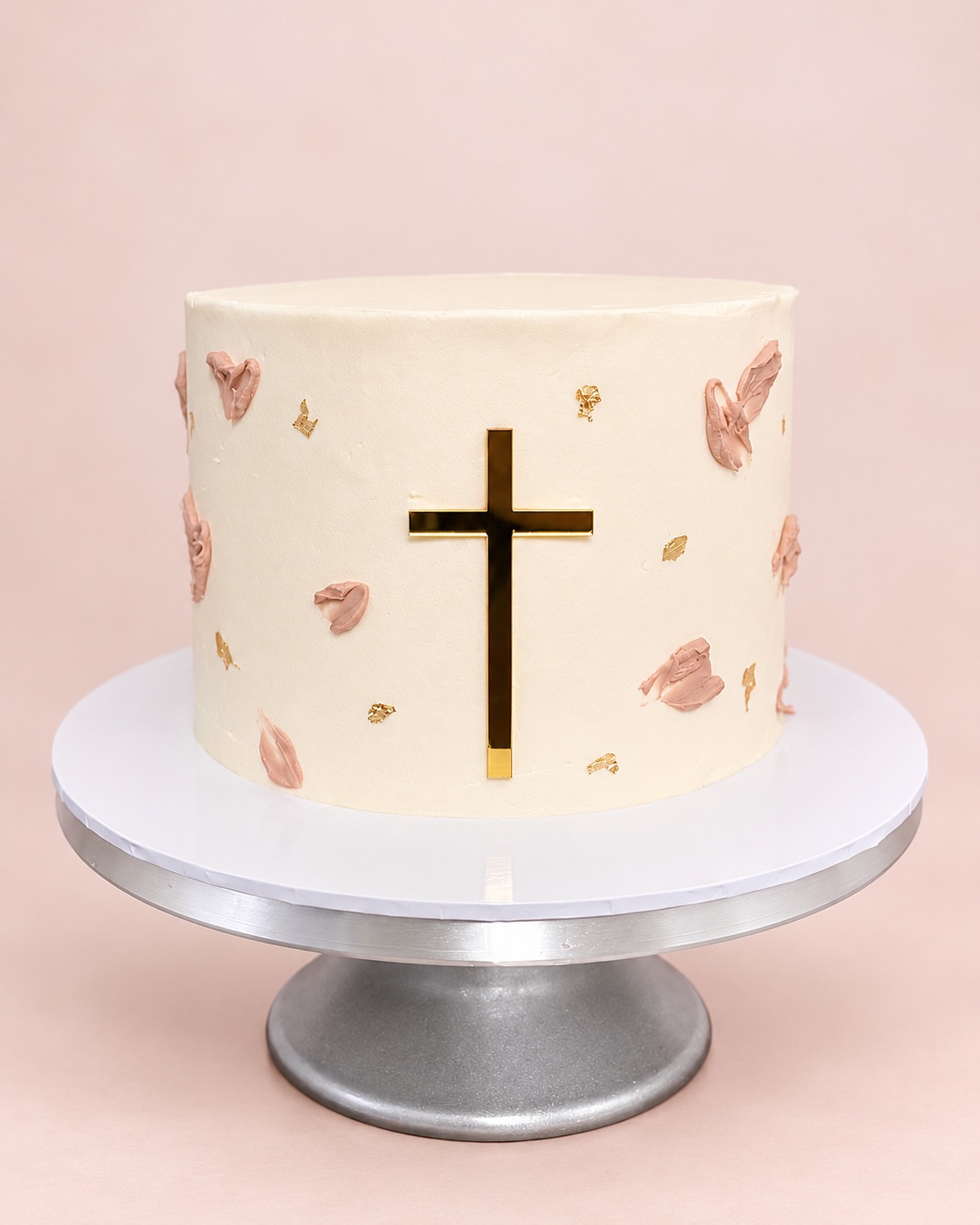 White buttercream christening cake with a gold cross, blush pink brushstroke petals and gold leaf